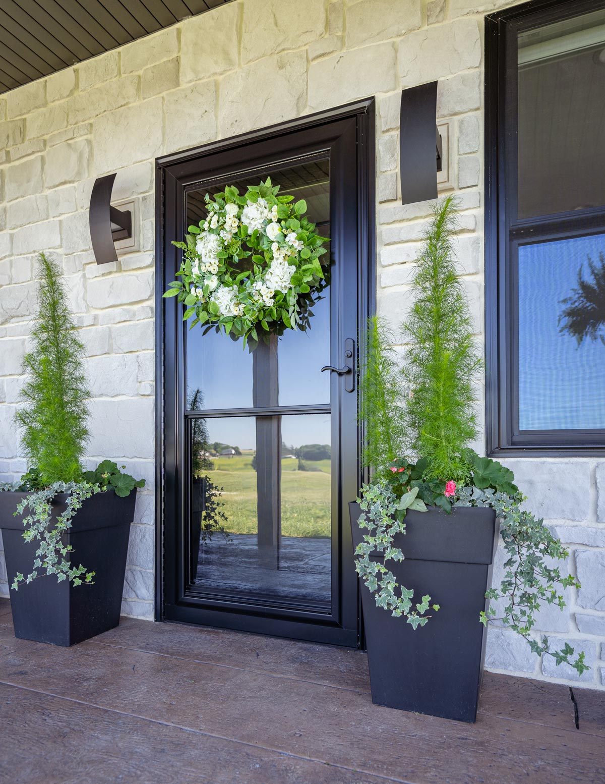 A front door with two large planters and a wreath.