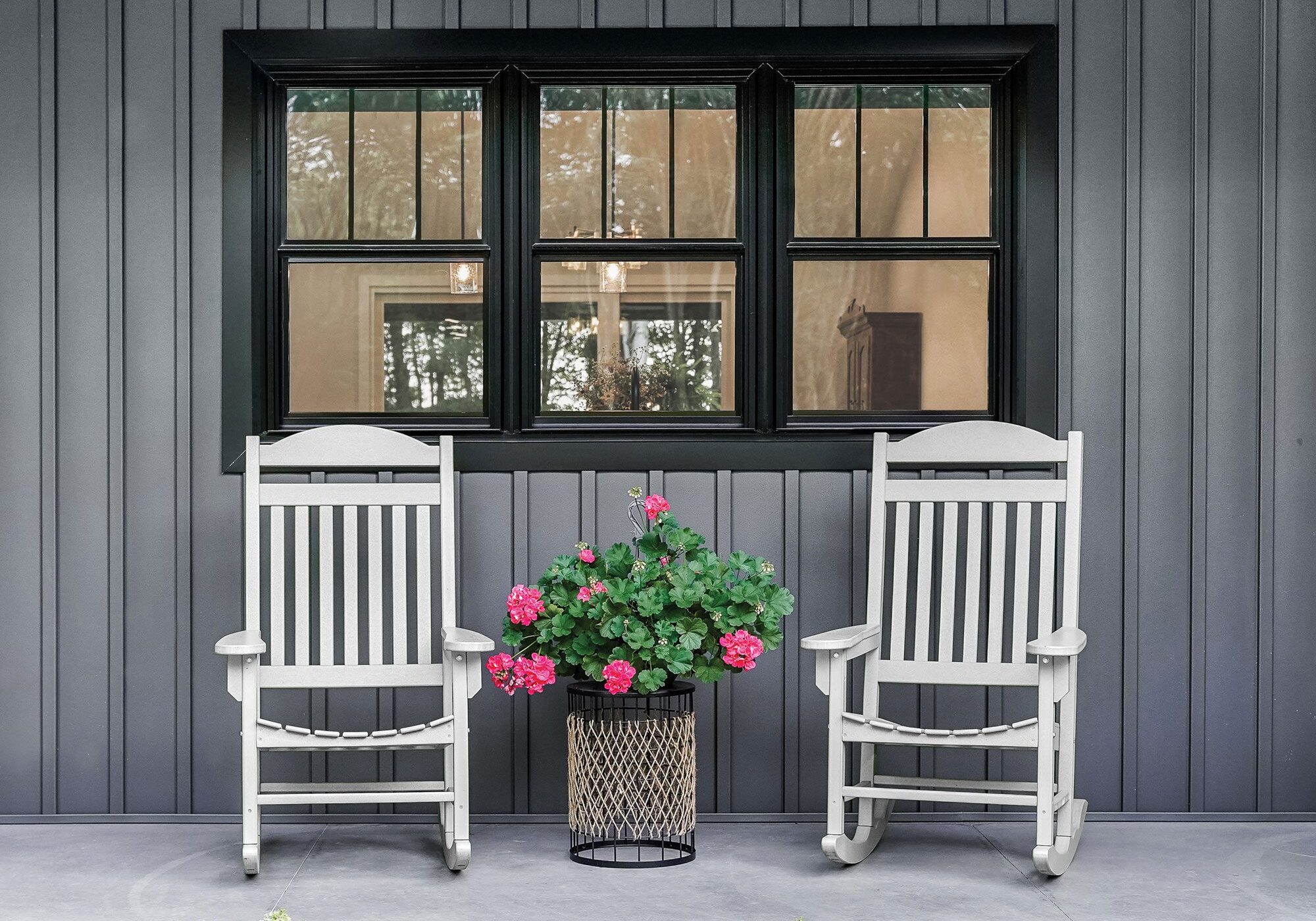 Two white rocking chairs sitting on a porch.