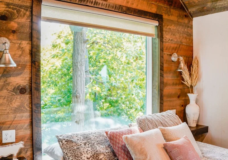 A bed with pillows and blankets in front of a window.