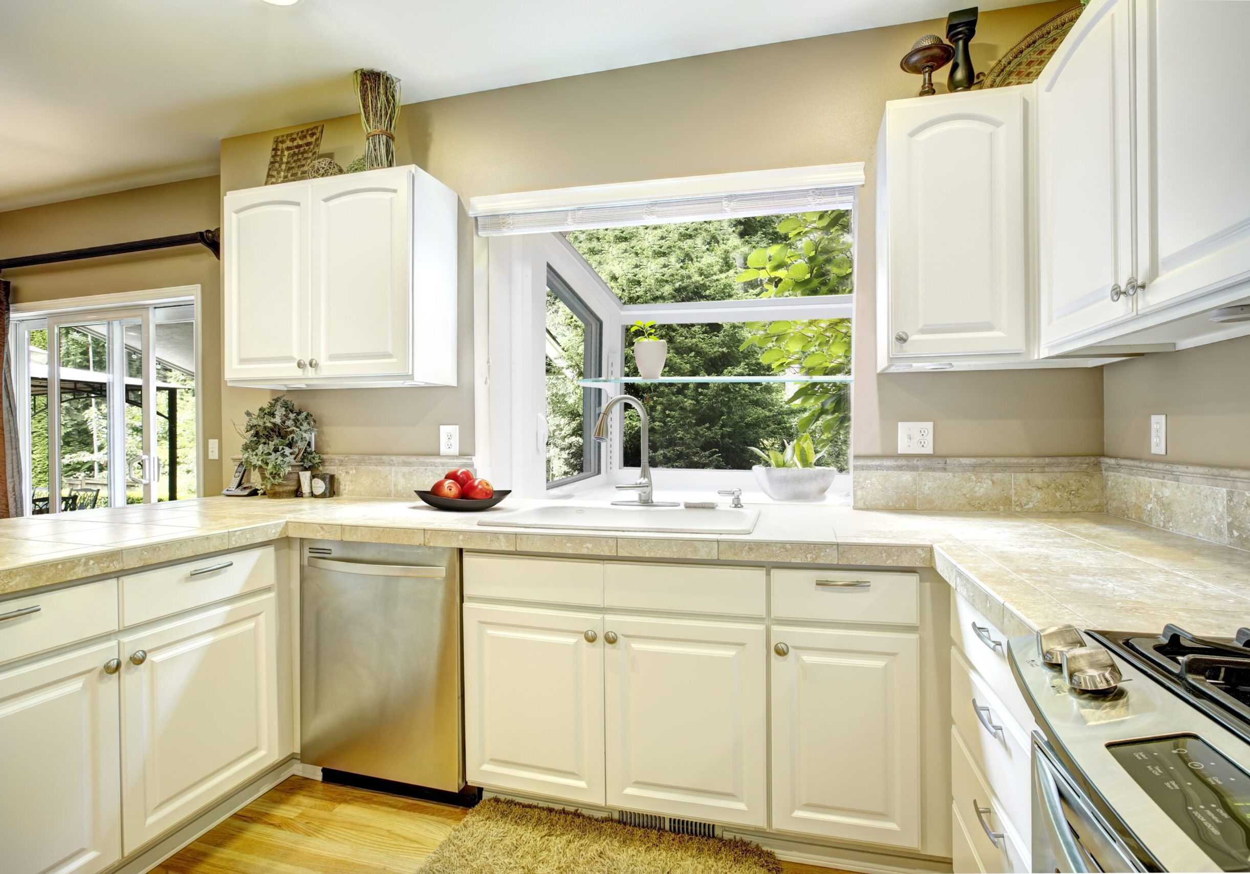A kitchen with white cabinets and wood floors.