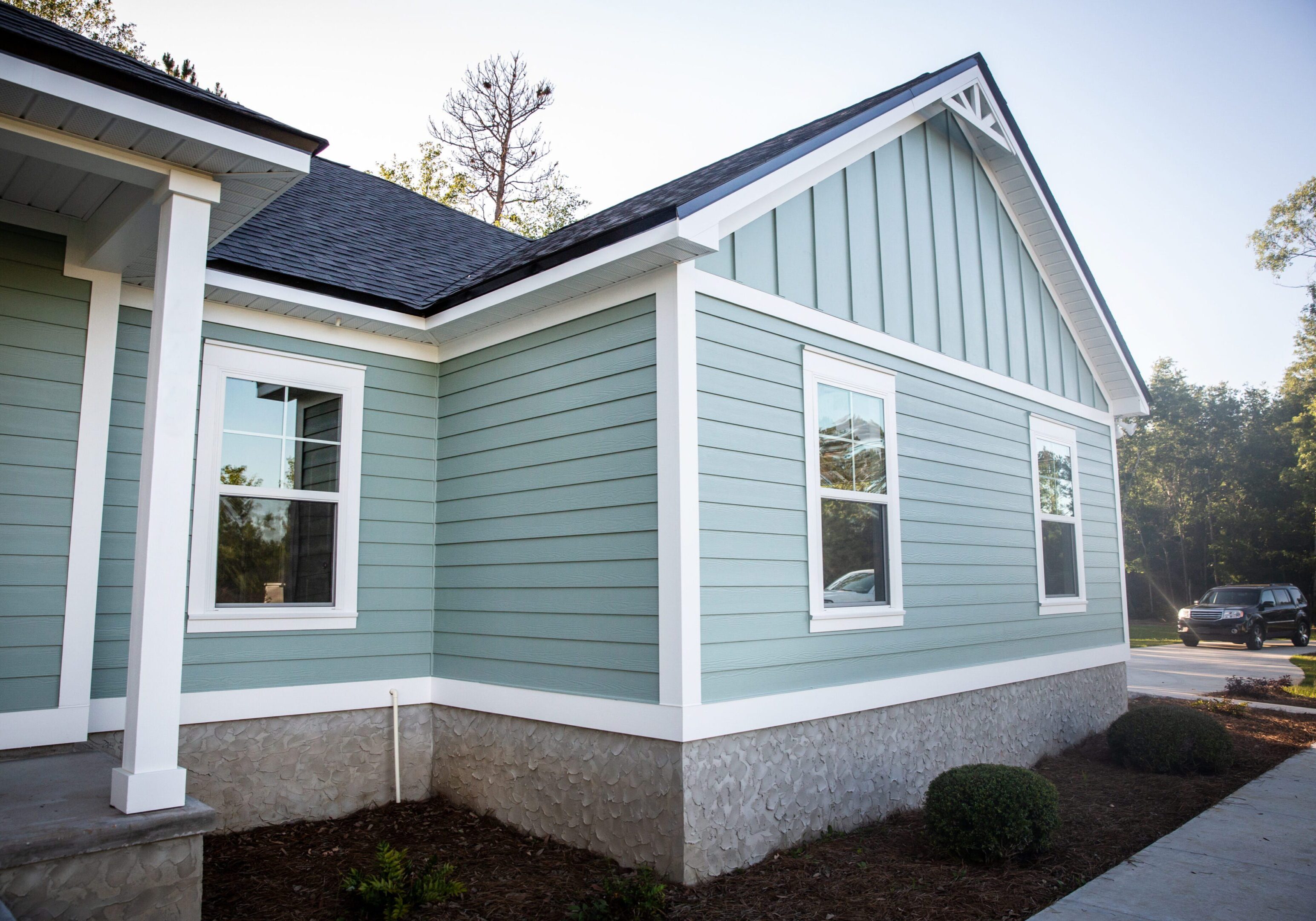 Front view of a brand new construction house with blue siding, a ranch style home with a yard Light blue house with white trim exterior.