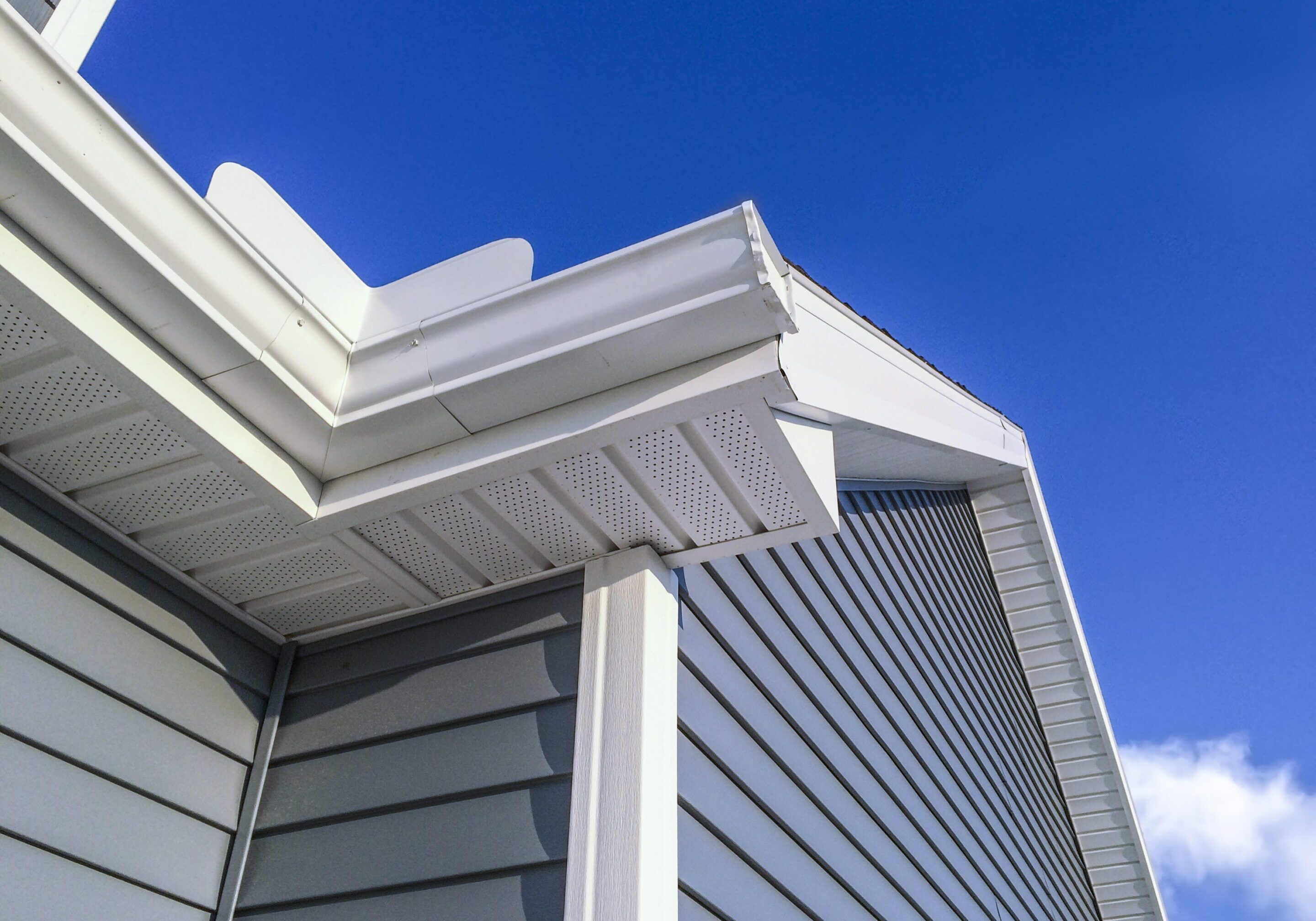 New soffit,gutters,vinyl siding House roof with blue sky background.