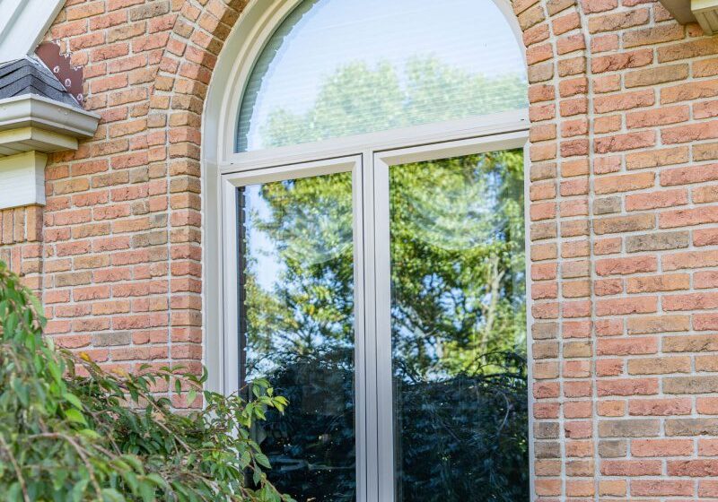 A brick building with two windows and bushes